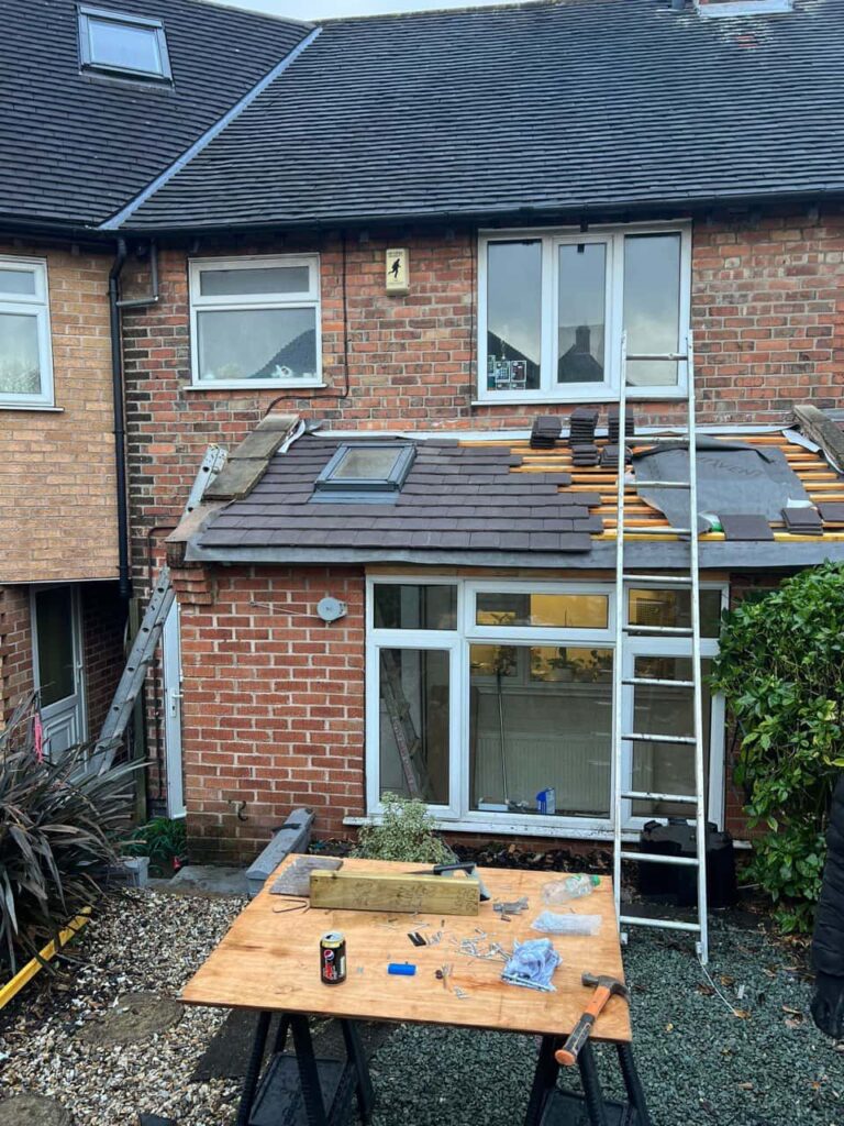 This is a photo of a roof extension that is having new roof tiles installed. This is a photo taken from the roof ridge looking down a tiled pitched roof on to a flat roof. Works carried out by LJ Roofing Bradford on Avon